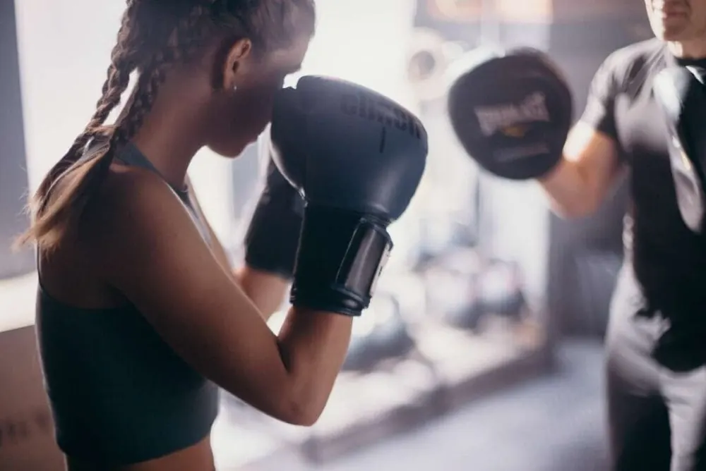 Member training with a coach on boxing pads