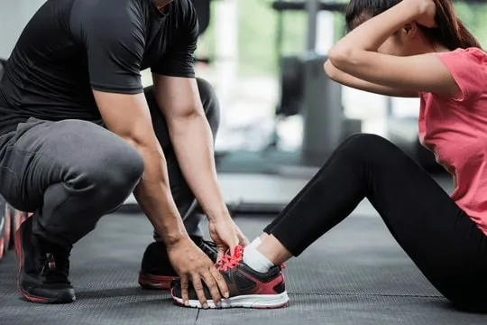 Trainer helping a member with a floor exercise